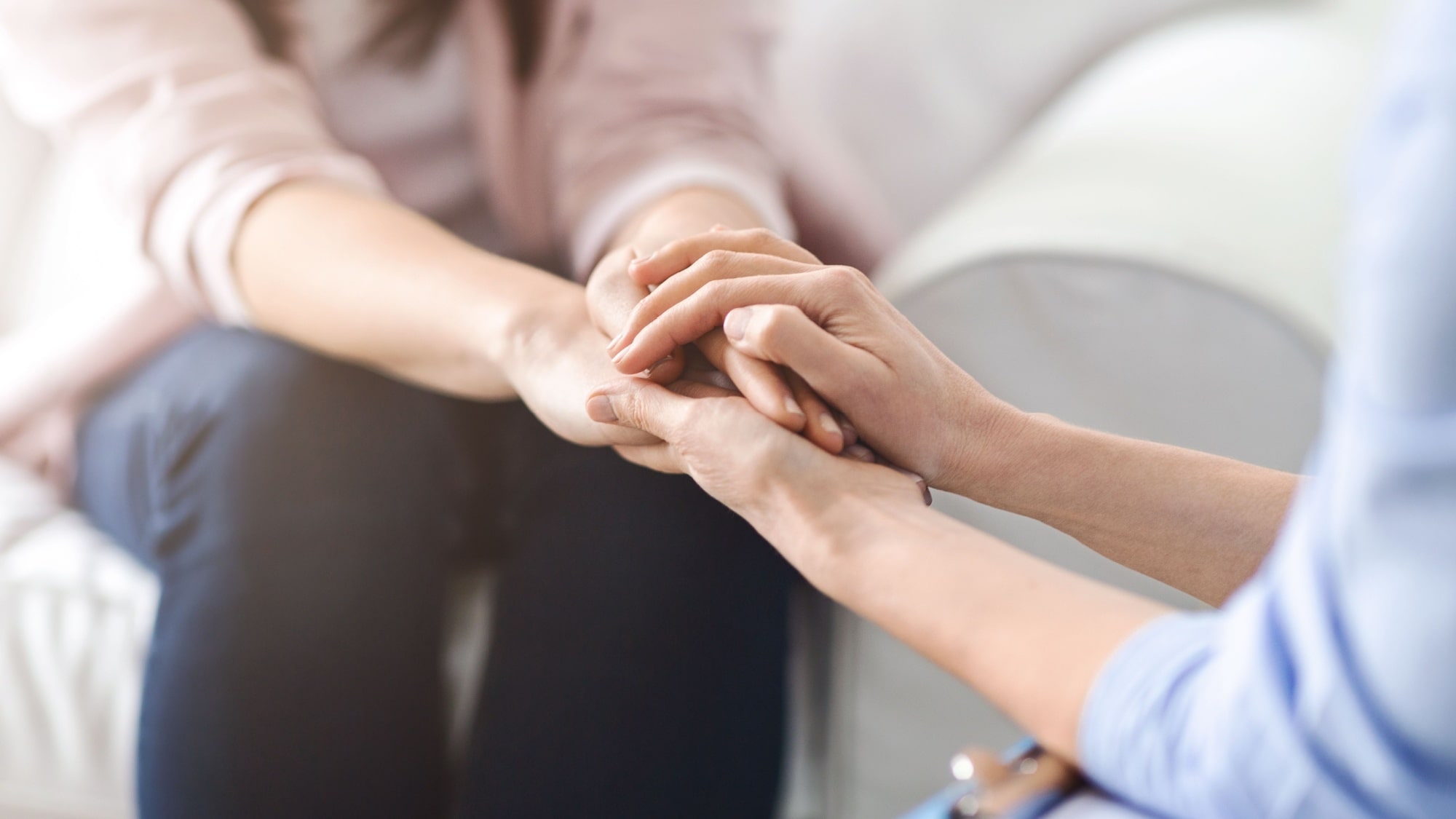 Woman offers comfort and reassurance by holding another woman hand