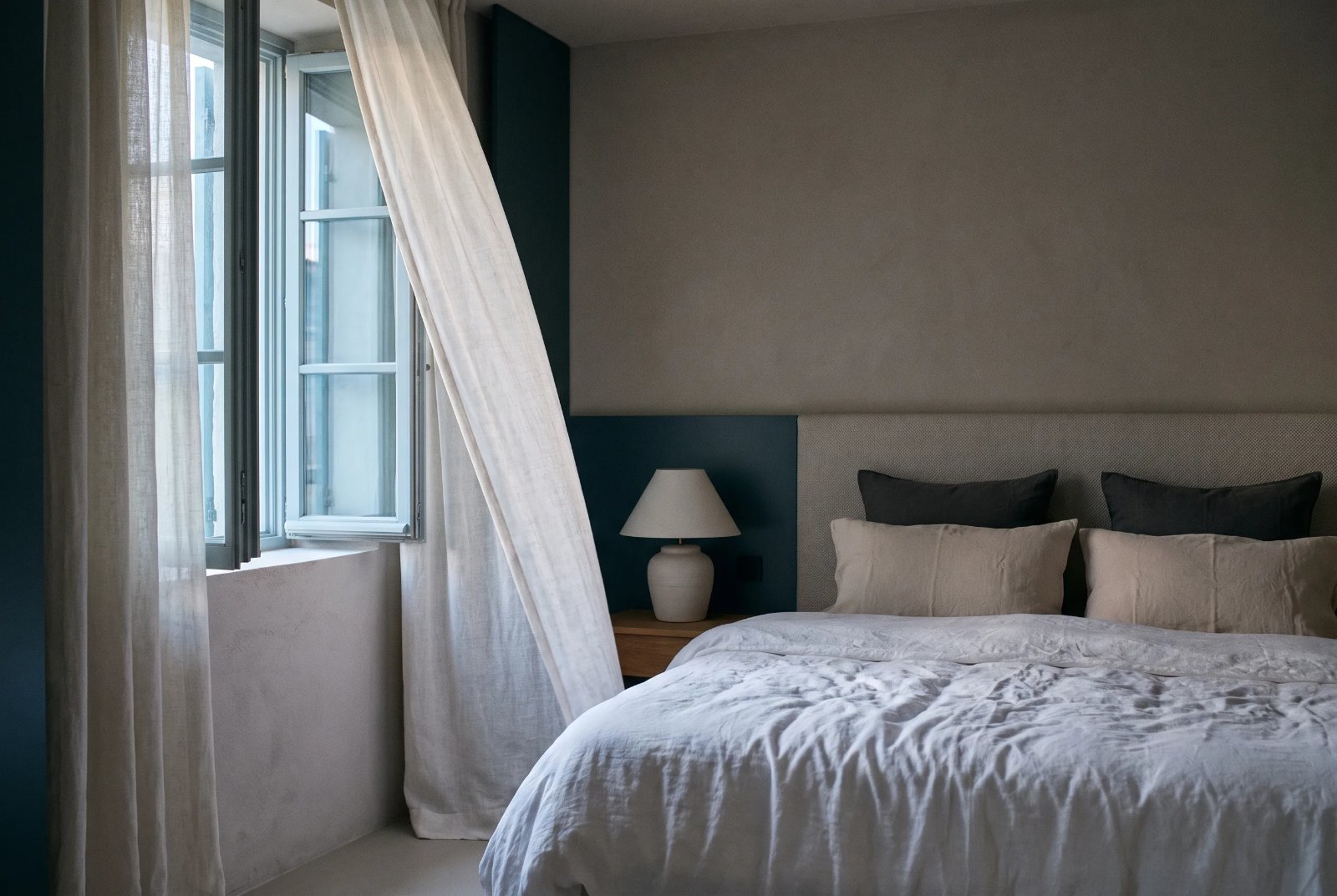 A quiet bedroom at dawn with sheer curtains at an open window